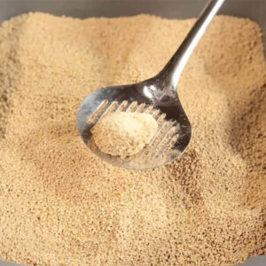 Close-up of clumping cat litter being scooped with a metal scoop in a litter box.